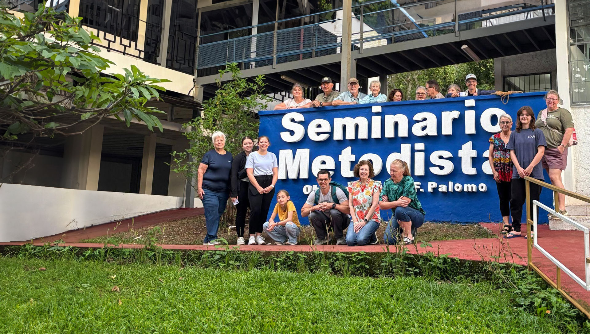 Group of mission team members in front of the blue "Seminario Metodista" sign in Costa Rica, highlighting the Lakewood Methodist Church's outreach efforts.